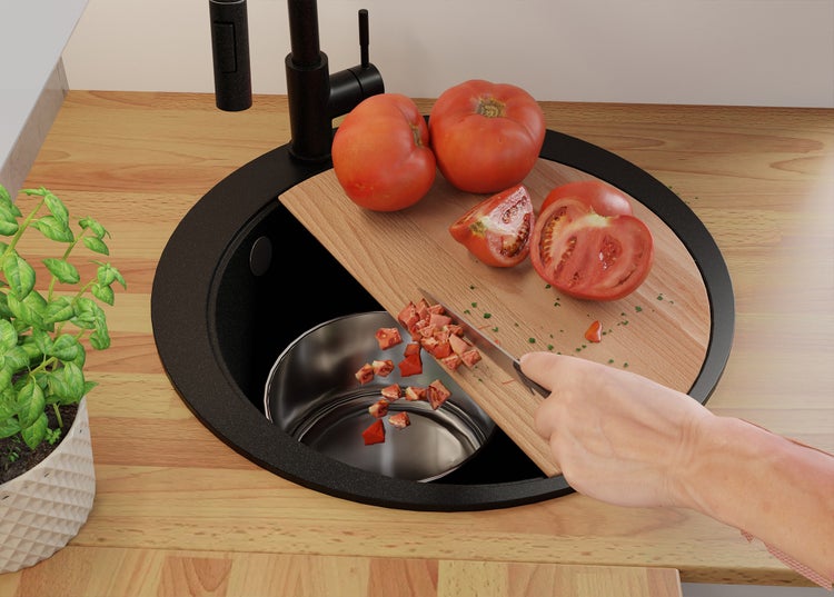 Küchenszene mit Spüle, Schneidebrett und Tomaten beim Schneiden