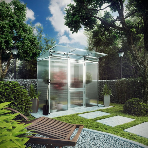Modernes Gewächshaus mit Aluminiumrahmen in einem hellen, organisierten Garten mit Rasen, Steinplatten, Gabionenwand und Bäumen.