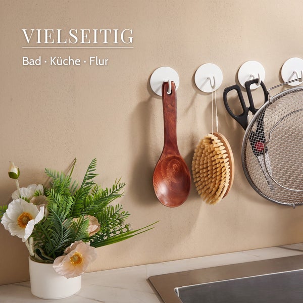 Mehrzweck Klebehaken an einer Wand in Küche oder Bad mit hängenden Küchenutensilien und einer Blumenvase.