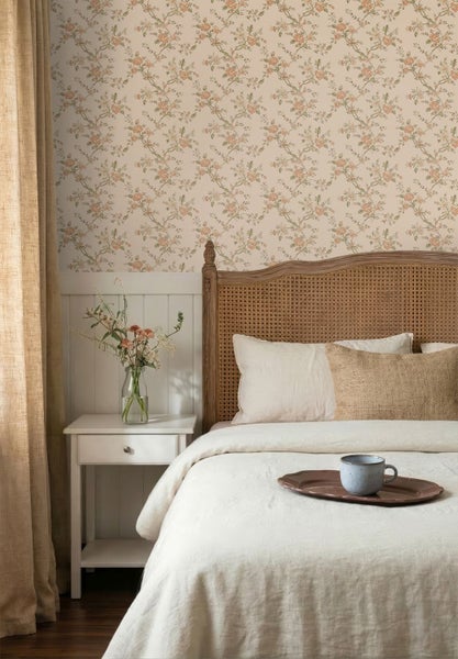 Schlafzimmer mit floraler Tapete, einem Holzbett mit Geflecht-Kopfteil, einem Nachttisch und Vorhängen im Landhausstil.