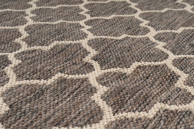 Nahaufnahme eines gewebten Teppichs mit geometrischem Gittermuster in Grau und Beige.