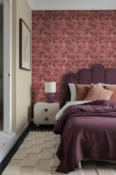 Schlafzimmer mit gemusterter Tapete, Bett, Nachttisch, Lampe und Teppich