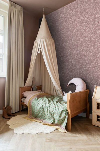 Kinderschlafzimmer mit Holzbett, Betthimmel aus Stoff, gemusterter Blumentapete und Fischgrätparkett.