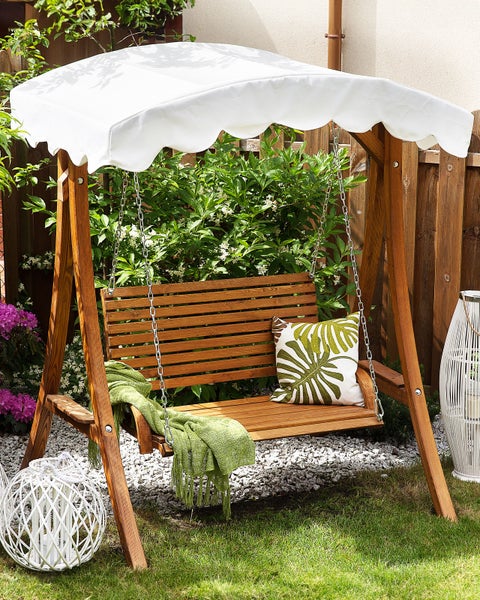 Holzschaukel mit Sonnendach, Kissen und Decke im Garten