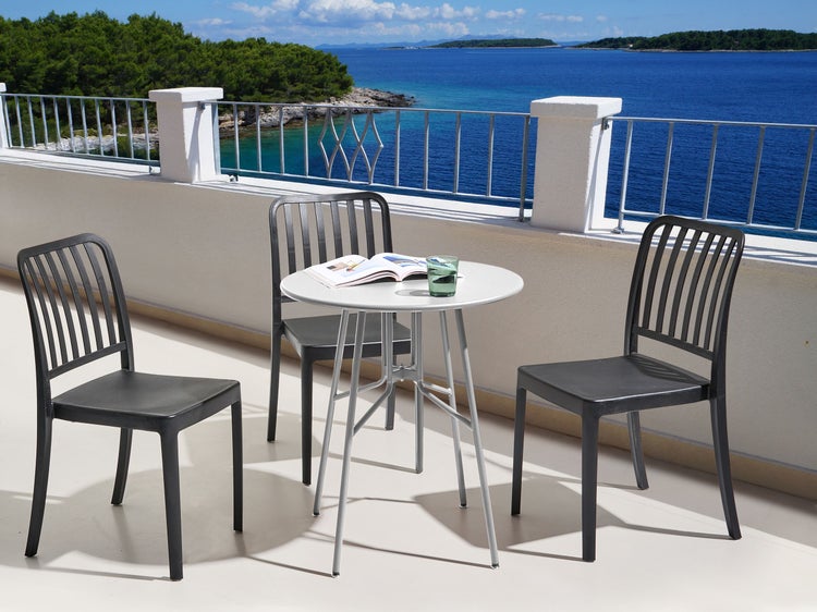 Gartenset mit Tisch und drei Stühlen auf einer Terrasse mit Meerblick