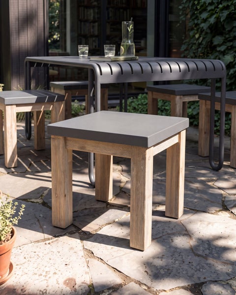 Gartentisch und Hocker Set mit Tischplatte aus Metall und Holzgestell auf einer Steinterrasse