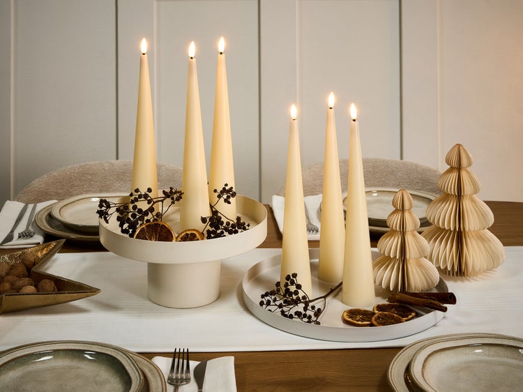 Dekorativer Tisch mit LED-Kerzen, getrockneten Orangenscheiben, Beeren und Papierweihnachtsbäumen