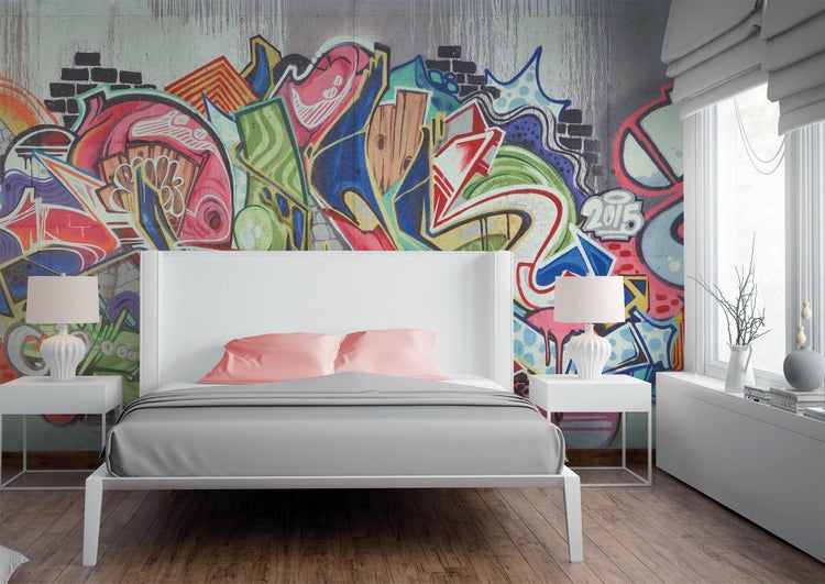 Modern eingerichtetes Schlafzimmer mit einer großflächigen Fototapete im farbenfrohen Graffiti-Stil an der Wand hinter dem weißen Bett.