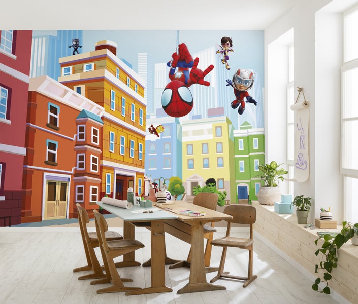 Helles Kinderzimmer mit Kindertapete, die eine Comic-Stadt mit Marvel-Superhelden darstellt, mit einem Holztisch und Stühlen in der Mitte des Raumes.