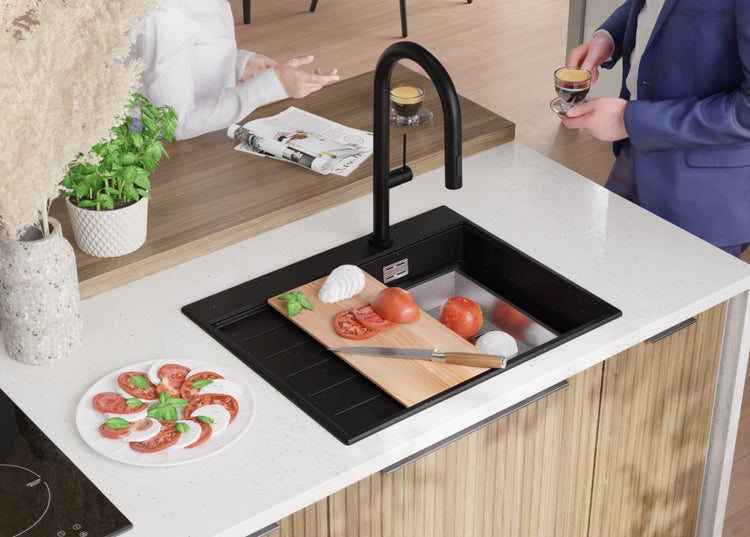 Küchenszene mit Spüle, Armatur, Schneidebrett, Lebensmitteln und Personen