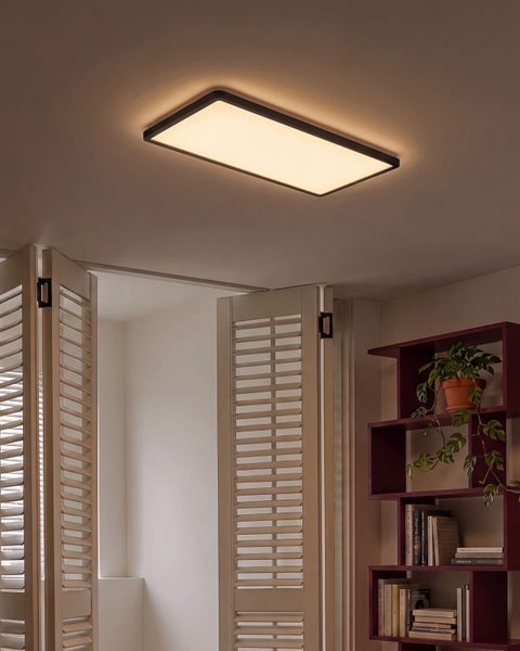 Rechteckige LED Deckenleuchte mit Rahmen montiert an einer Zimmerdecke in einem Wohnbereich mit Lamellentüren und Regal.