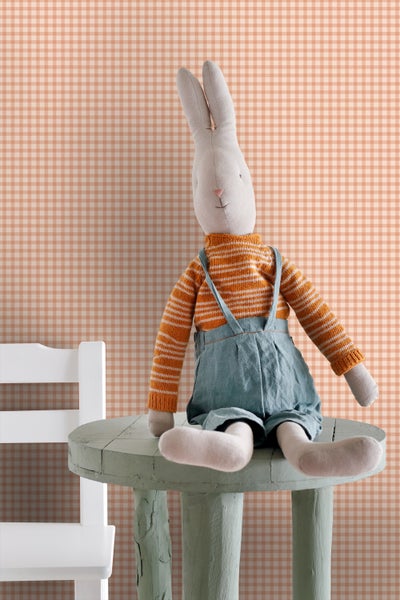 Stoffhase mit gestreiftem Pullover und Latzhose sitzt auf einem Hocker