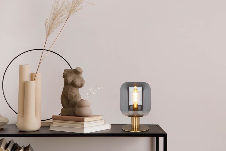 Dekorative Szene mit Lampe, Büchern und Dekoration auf einem Tisch.