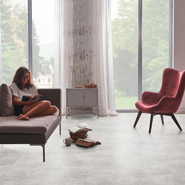 Heller Wohnraum mit Sofa, Sessel, Kommode und Fensterfront