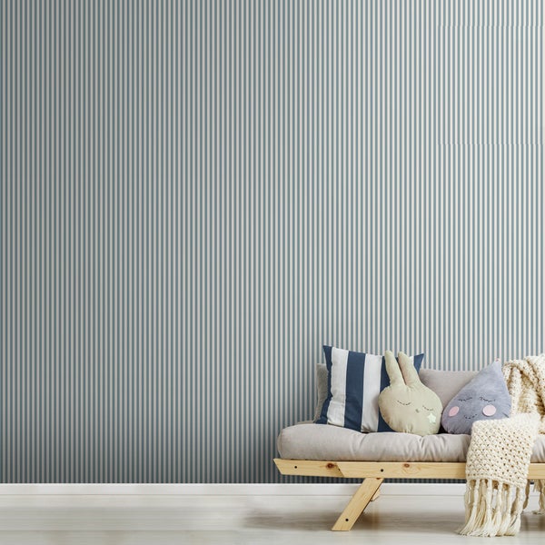Gestreifte Tapete an einer Wand in einem Zimmer mit Holzbank, Dekokissen und Strickdecke.