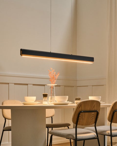 Moderne, schwarze LED-Pendelleuchte aus Holz und Metall über einem Esstisch mit Stühlen in einem hellen, aufgeräumten Esszimmer.