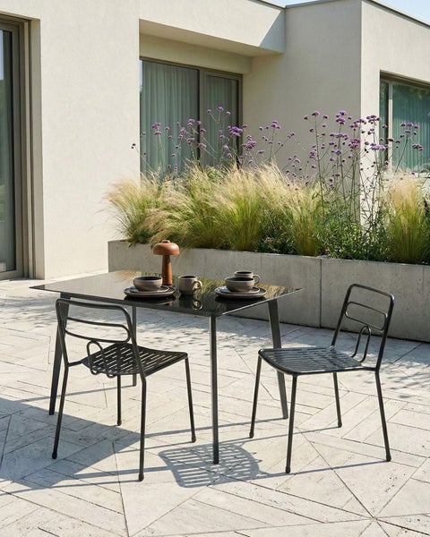 Gartenszene mit Esstisch, Stühlen, Geschirr und Pflanzen