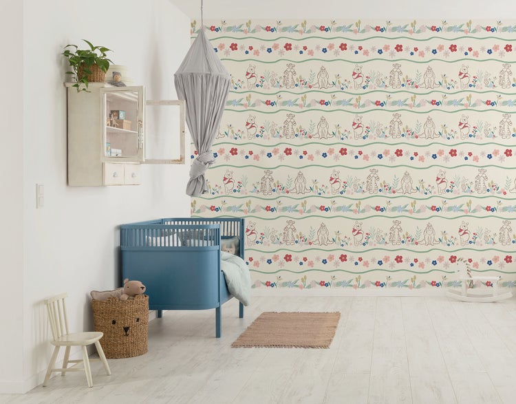 Helles Kinderzimmer mit blauem Gitterbett, gemusterter Winnie Puh Tapete und Holzfußboden.
