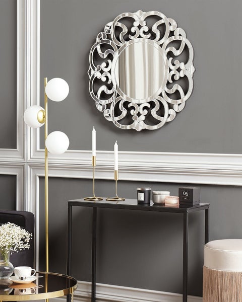 Dekoratives Interieur mit Spiegel, Tischleuchte, Beistelltisch und Dekorationsartikeln