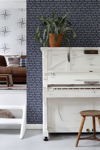Wohnraum mit Sofa, Kissen, Tapete mit nautischem Motiv und weißem Klavier