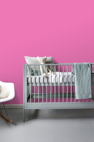 Zimmer mit pinkfarbener Tapete, Babybett und Schaukelstuhl
