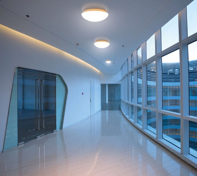 Heller Bürokorridor mit Glasfenstern und moderner Beleuchtung
