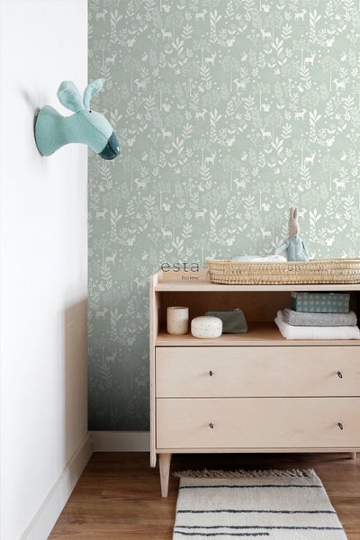 Ein Kinderzimmer mit einer Kommode und einer Tapete mit Waldtiermotiven