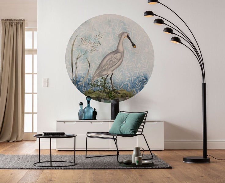 Wohnzimmer mit Wandbild, Sideboard, Sessel, Stehlampe und Beistelltisch auf einem grauen Teppich