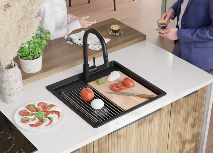 Küchenspüle mit Armatur, Schneidebrett, Tomaten und Mozzarella auf einer Arbeitsplatte