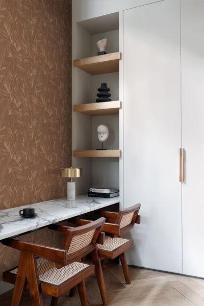 Moderne Arbeitsecke mit Marmorschreibtisch, Rattanholzstühlen, Einbauschrank und Wandtapete mit Blattmuster.