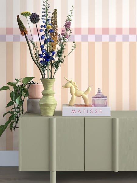 Dekoratives Stillleben mit Blumen, Pflanzen und Zierobjekten auf einem Sideboard