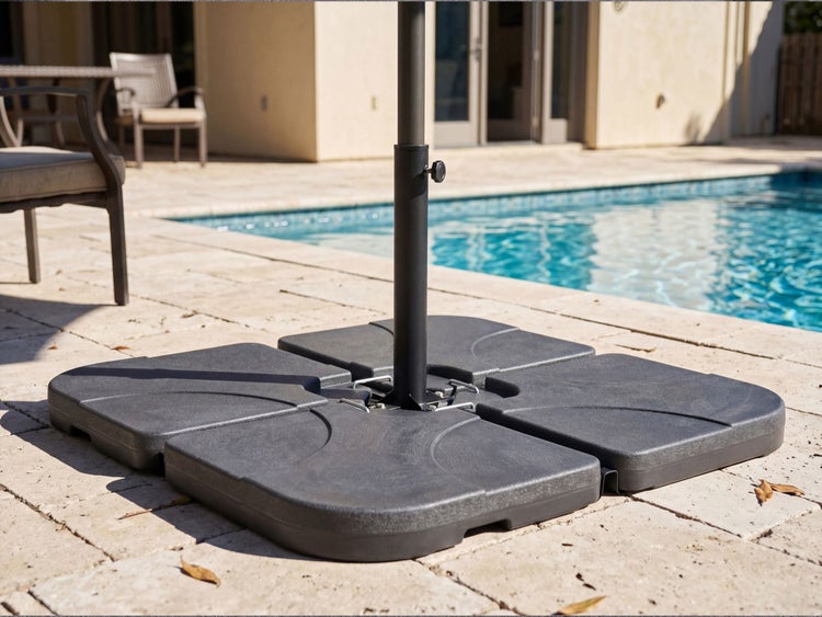 Vierteiliger, befüllbarer Sonnenschirmständer aus Kunststoff auf einer Steinterrasse neben einem Swimmingpool.