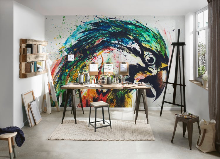 Fototapete mit Papageienmotiv in einem hellen Künstleratelier mit Holzschreibtisch, Staffelei und Wandregal aus Palettenholz.