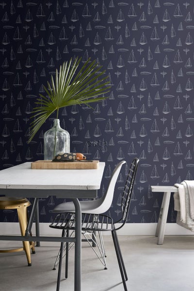 Innenraum mit Tisch, Stühlen und Tapete mit Segelbootmotiv.