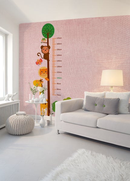 Helles Zimmer mit weißem Sofa und Messlatte-Wandtattoo mit Tieren auf rosa strukturierter Wand. Modernes und kinderfreundliches Design.