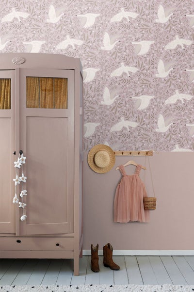 Kinderzimmer mit Schwanentapete, einem hölzernen Kleiderschrank, einer Garderobenleiste mit Kleidung und Stiefeln auf dem Boden.