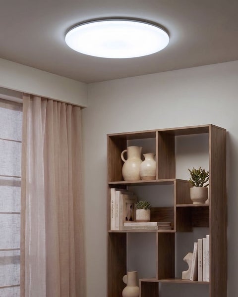 Moderne runde LED Deckenleuchte in einem wohnlich eingerichteten Raum mit Holzregal und Dekoration.