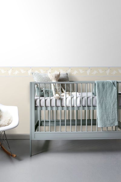 Kinderzimmer mit Gitterbett, Spielzeug und Bordüre mit Tiermotiv