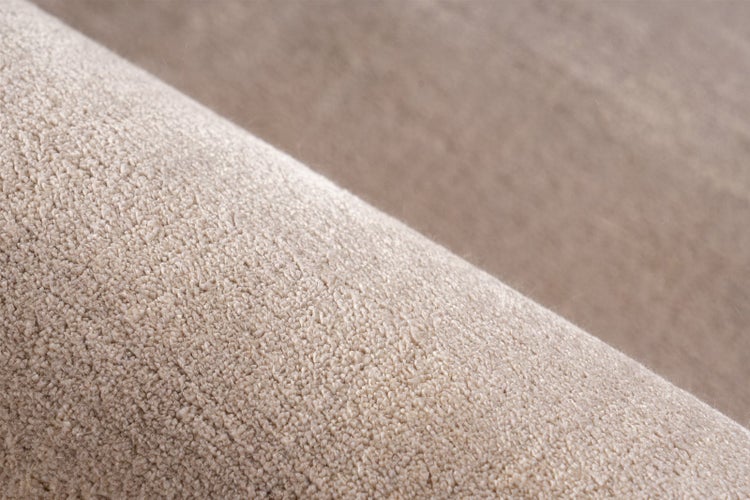 Nahaufnahme eines beigen Teppichbodens mit einer dichten und weichen Florstruktur.