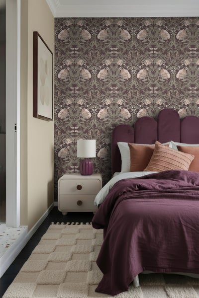 Schlafzimmer mit gemusterter Tapete, Bett, Nachttisch und Teppich