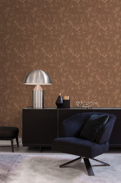 Wohnzimmer mit dunklem Sideboard, Sessel und moderner Tischlampe vor einer Tapete mit tropischem Blattmuster