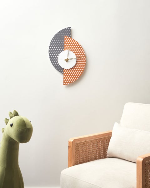 Dekorative Wanduhr mit Punktmuster neben Sessel und Stofftier
