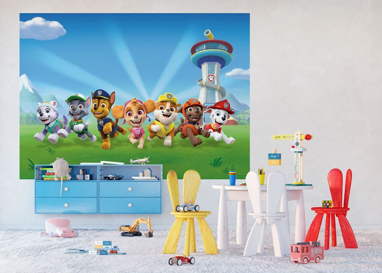Fototapete Paw Patrol in einem hellen Kinderzimmer mit einem blauen Schrank, Tisch, bunten Stühlen in Hasenform und Spielzeug auf dem Boden.