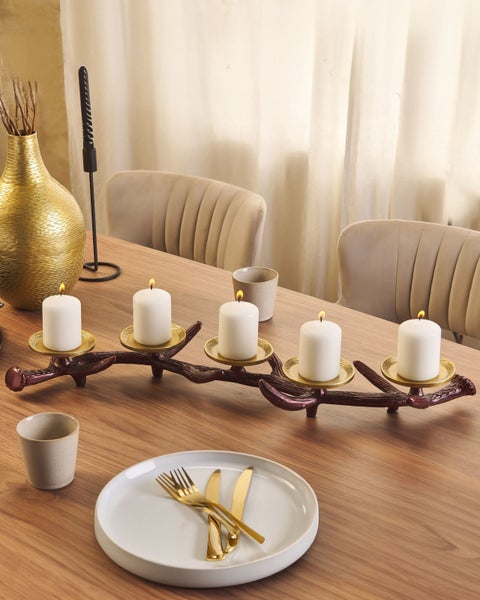 Dekorativer Tisch mit Kerzen, Geschirr und Vase für eine warme Atmosphäre