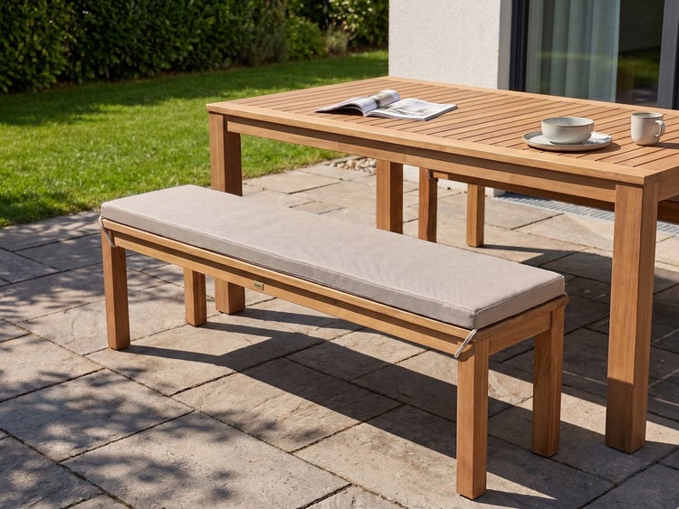 Gartenbank aus Holz mit einem bequemen Sitzkissen auf einer Terrasse stehend, neben einem passenden Gartentisch.