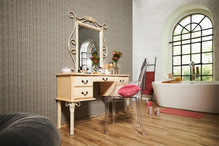 Badezimmer mit Waschtisch, Spiegel und transparentem Stuhl.