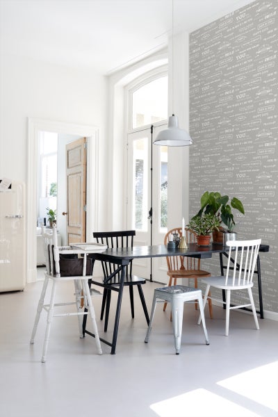 Heller Essbereich mit Esstisch und verschiedenen Stühlen vor einer gemusterten Tapete