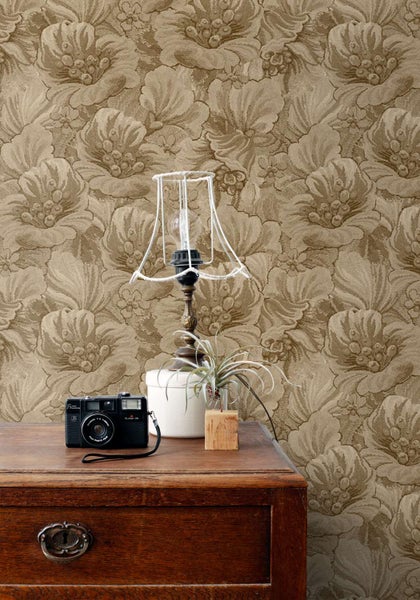 Wohnraum mit Tapete mit floralem Muster auf einer Holzkommode mit einer Lampe ohne Schirm und einer analogen Kamera.