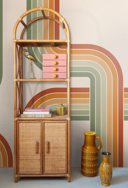 Regal aus Rattan mit Deko-Elementen in einem Raum mit Streifenmuster an der Wand