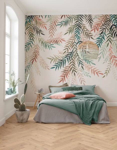 Schlafzimmer mit Blättertapete, Bett, Nachttisch, Lampe und Kaktus